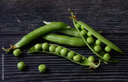 Fresh green pea pod with beans isolated on dark wooden background. Fresh pods of green peas horizontal composition isolated on a old rustic wooden surface close up, soft focus