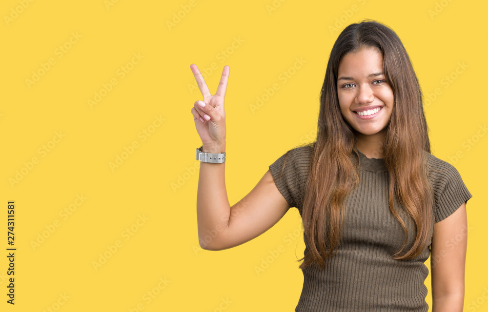 Young beautiful brunette woman over isolated background smiling with happy face winking at the camera doing victory sign. Number two.