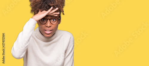 Beautiful young african american woman wearing glasses over isolated background very happy and smiling looking far away with hand over head. Searching concept. photo