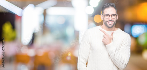Young handsome man wearing glasses over isolated background cheerful with a smile of face pointing with hand and finger up to the side with happy and natural expression on face