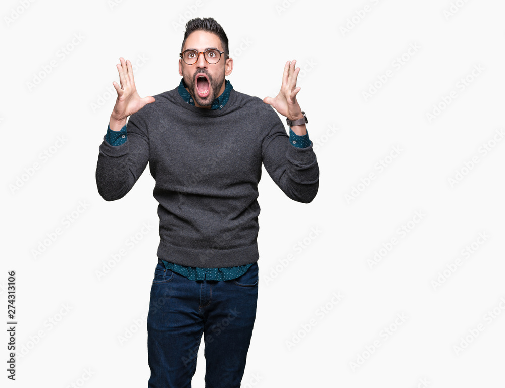 Young handsome man wearing glasses over isolated background celebrating crazy and amazed for success with arms raised and open eyes screaming excited. Winner concept Young handsome man wearing glasses over isolated background celebrating crazy and amazed for success with arms raised and open eyes screaming excited. Winner concept