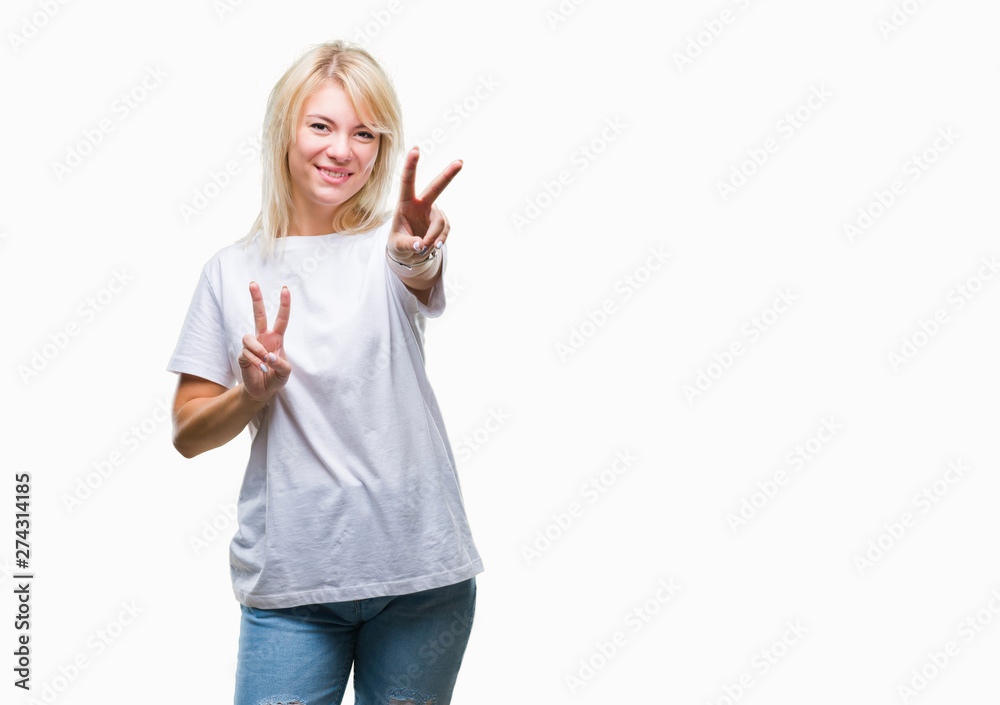 Obraz premium Young beautiful blonde woman wearing white t-shirt over isolated background smiling looking to the camera showing fingers doing victory sign. Number two.