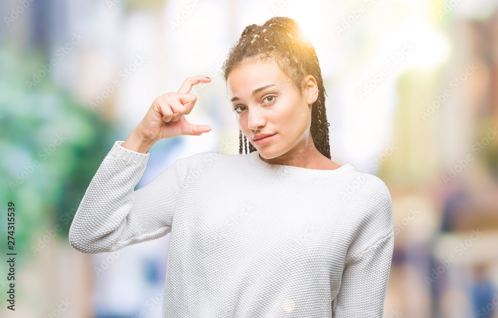Young braided hair african american girl wearing winter sweater over isolated background smiling and confident gesturing with hand doing size sign with fingers while looking and the camera Young braided hair african american girl wearing winter sweater over isolated background smiling and confident gesturing with hand doing size sign with fingers while looking and the camera