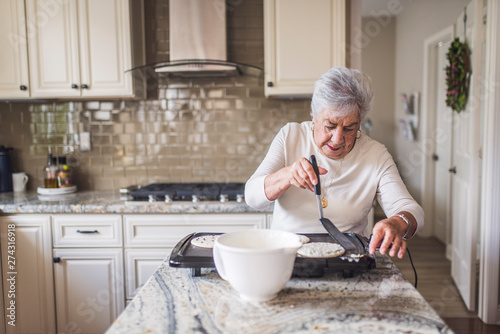 Portrait of senior woman cooking pancakes for breakfast photo