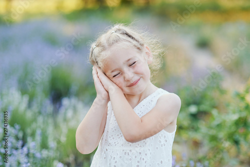 Little girl in lavender field. kids fantasy. Smiling girl sniffing flowers in summer purple lavender field.