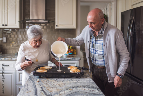 Great grandma cooking pancakes with her adult son photo