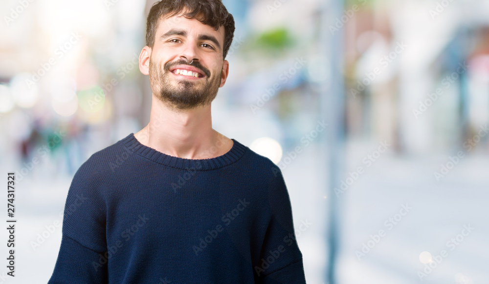 Young handsome man over isolated background Hands together and fingers crossed smiling relaxed and cheerful. Success and optimistic
