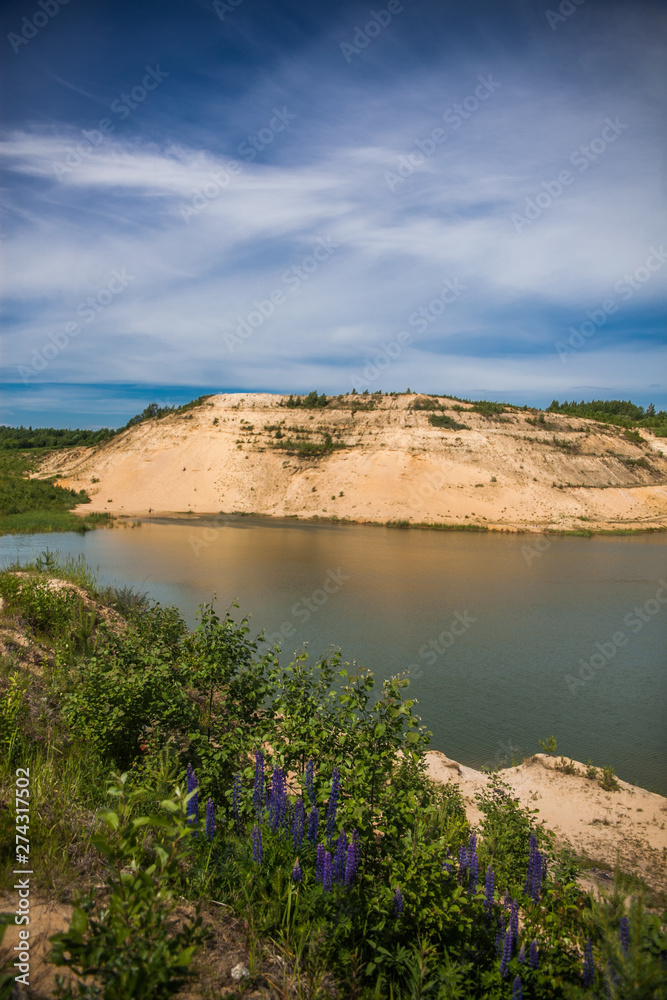 Blue sky and lake in the sand quarry with green grass