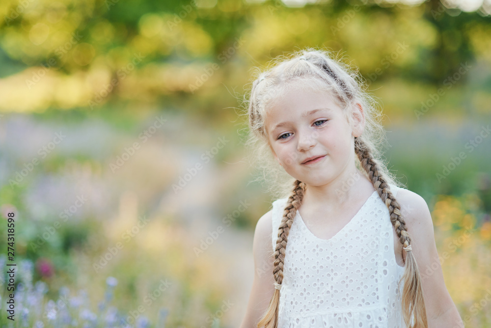 Naklejka premium Little girl in lavender field. kids fantasy. Smiling girl sniffing flowers in summer purple lavender field.