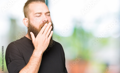 Young blond man wearing casual t-shirt bored yawning tired covering mouth with hand. Restless and sleepiness.