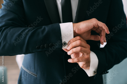 Close-up groom hands puts on cufflinks. Elegant gentleman clothers, white shirt