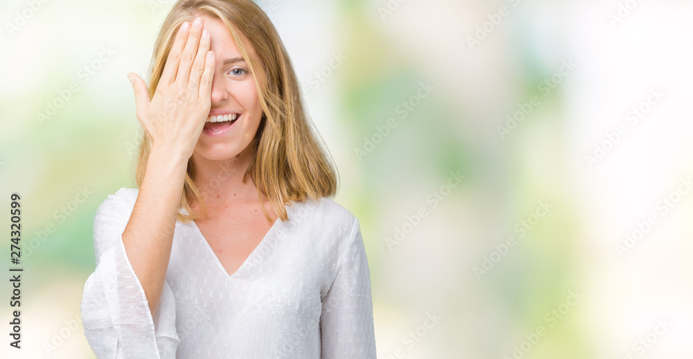 Beautiful young elegant woman over isolated background covering one eye with hand with confident smile on face and surprise emotion. Beautiful young elegant woman over isolated background covering one eye with hand with confident smile on face and surprise emotion.
