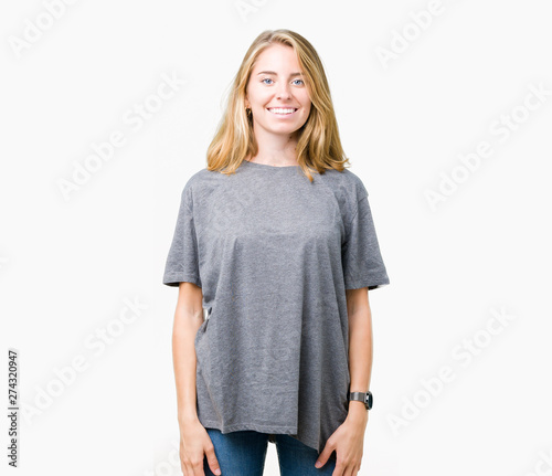 Beautiful young woman wearing oversize casual t-shirt over isolated background with a happy and cool smile on face. Lucky person.