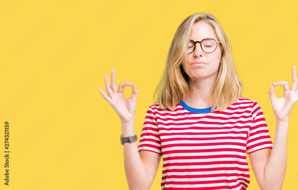 Beautiful young woman wearing glasses over isolated background relax and smiling with eyes closed doing meditation gesture with fingers. Yoga concept.