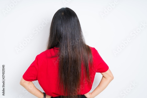 Beautiful brunette woman wearing red t-shirt over isolated background standing backwards looking away with arms on body