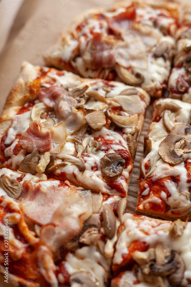 Macro close up of a roman square pizza on thick dough with champignons and a lot of cheese, served on craft paper