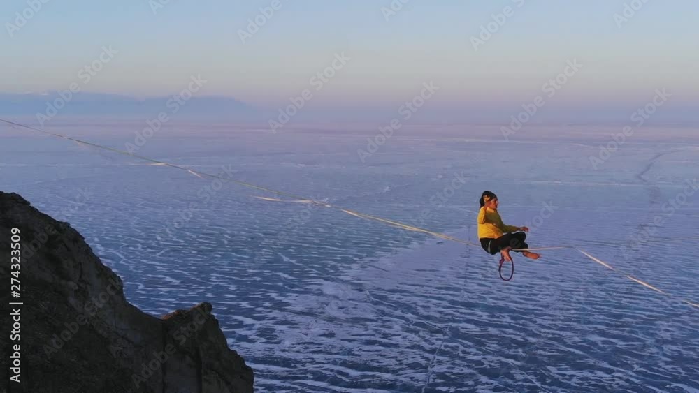 A woman meditates sitting on a stretched sling high in the mountains. A woman meditates sitting on a stretched sling high in the mountains.