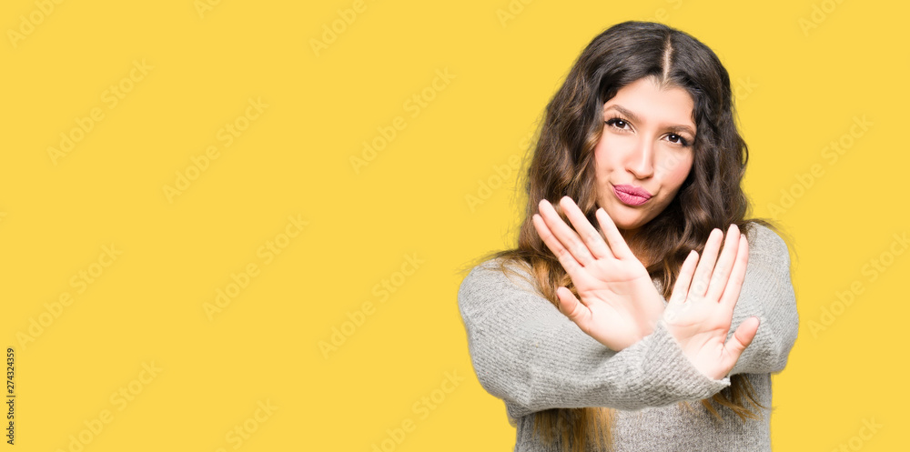 Young beautiful woman wearing winter dress Rejection expression crossing arms and palms doing negative sign, angry face