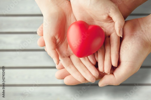 Obraz na plátně Man and woman holding red heart on background