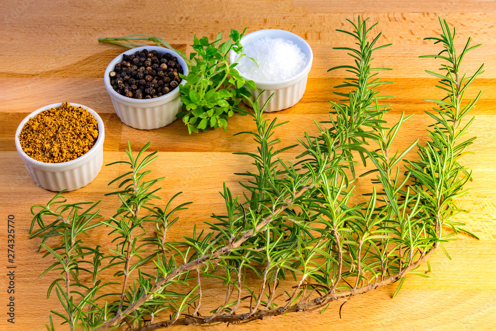 Different spices, rosemary, thyme, pepper, salt and steak rub for bbq on a wooden board, kitchen background. Different spices, rosemary, thyme, pepper, salt and steak rub for bbq on a wooden board, kitchen background.