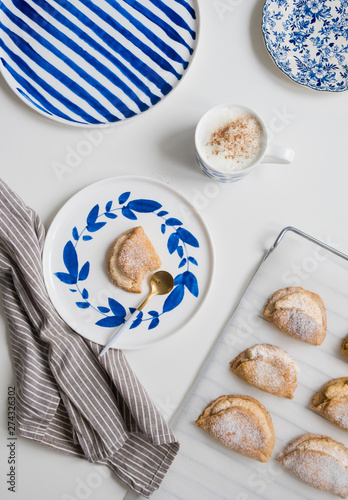 Delicious homemade dessert on blue plates. Shortbread sweet with coffee in a white mug. teaspoon golden. Saucer with earrings of leaves and stripes. On a white background.