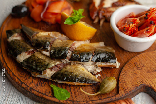 Close up of smoked mackerel pieces and smoked shrimps as a part of seafood dish ? perfect party snack for beer and wine, served on wooden board