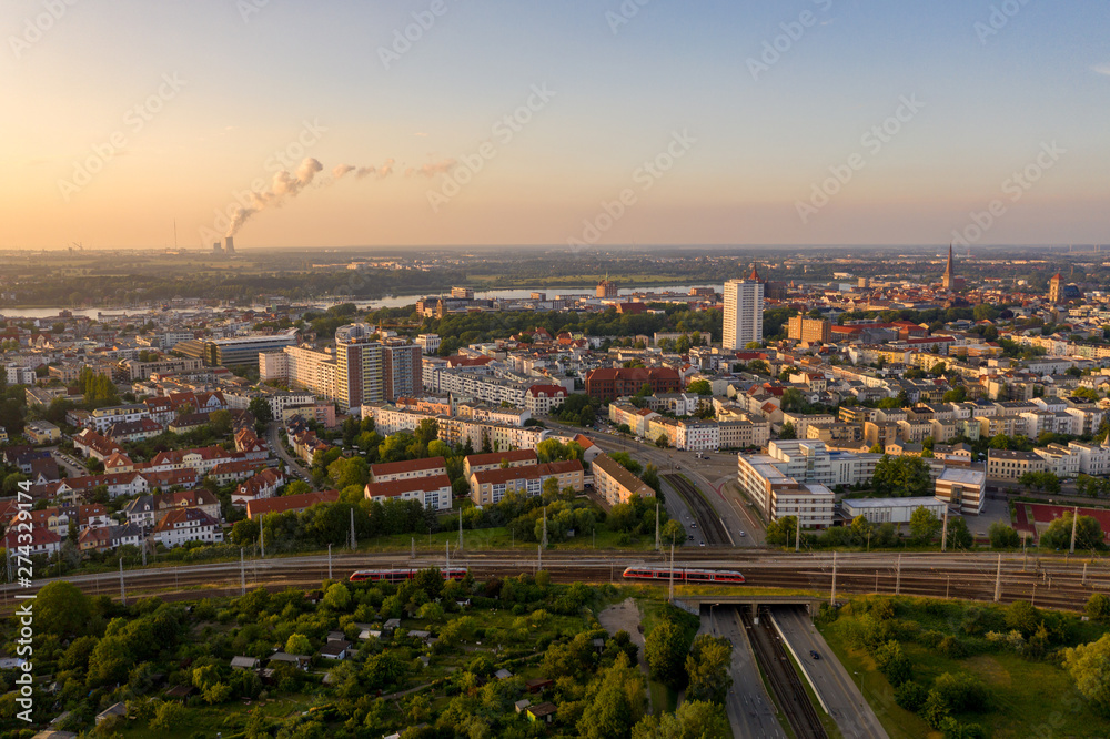 aerial view of the city of rostock, railway tracks, river warnow and power plant chimney in the background