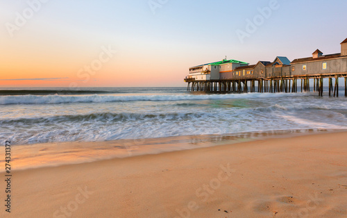 Beautiful sunrise over Old Orchard Beach Pier  Saco Maine USA. The wooden pier on the beach contains many other tourist businesses  including a variety of souvenir shops.