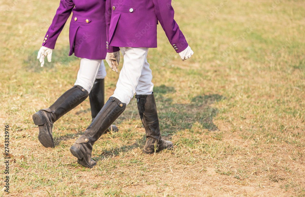 Young girl equestrians in professional apparel dressage purple jacket competition with black leather horseman boots walking in the field Young girl equestrians in professional apparel dressage purple jacket competition with black leather horseman boots walking in the field