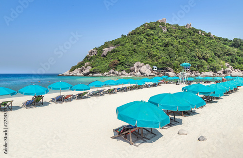 Landscape view of row blue umbrellas with wooden beach chairs on tropical sandy beach in sunny day at Koh Nang Yuan Island Surat Thani, Thailand summer holidays concept 