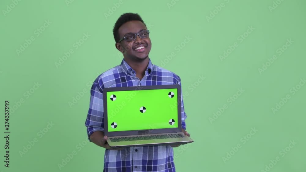 Happy young African hipster man thinking while showing laptop Happy young African hipster man thinking while showing laptop