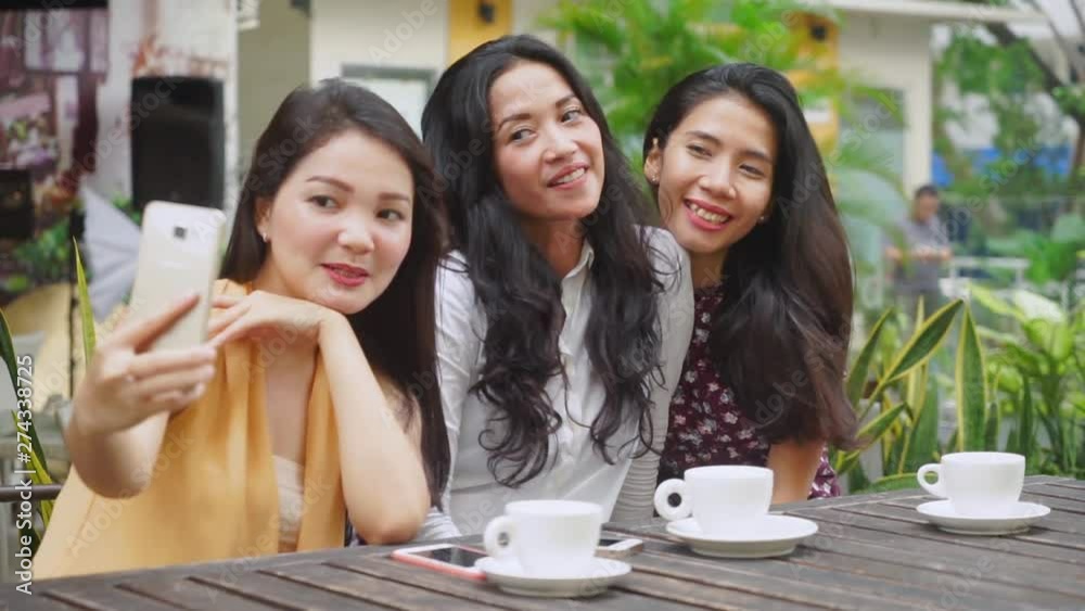 Group of cheerful women taking selfie photo together with a mobile phone in the cafe Group of cheerful women taking selfie photo together with a mobile phone in the cafe
