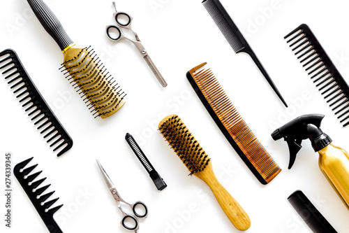 professional accessories of hairdresser with combs and spray on work desk white background top view pattern