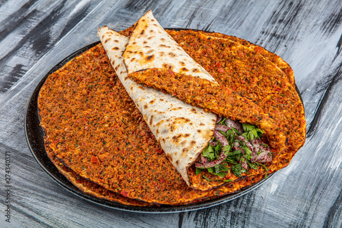 Traditional Turkish Cuisine: Lahmacun turkish delicious pizza with minced beef or lamb meat, paprika, tomatoes, cumin spice, on rustic wooden table background. photo