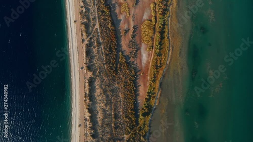 AERIAL TOP DOWN Car driving on isthmus road between two lakes shore