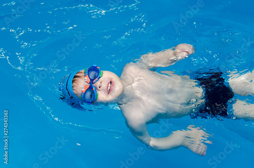 little boy learns to swim in the pool