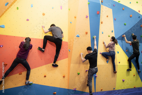Young friends climbing a climbing wall at gym photo