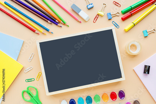 School supplies stationery, colour pencils, paints, paper on pastel orange background, back to school concept with free copy space for text, modern elementary education. Kids desk, flat lay