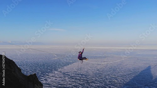 Young woman on the Highline. Tightrope Walker doing yoga at high altitude.