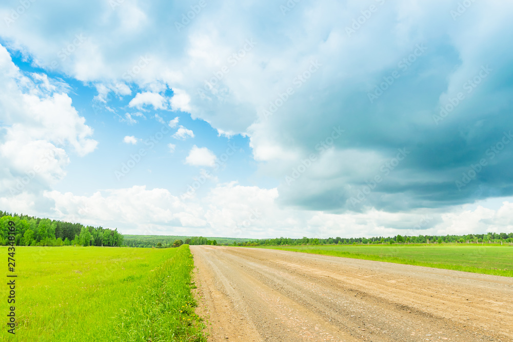 Landscape rural road and blue sky. Straight gravel road leading to the horizon. Landscape rural road and blue sky. Straight gravel road leading to the horizon.