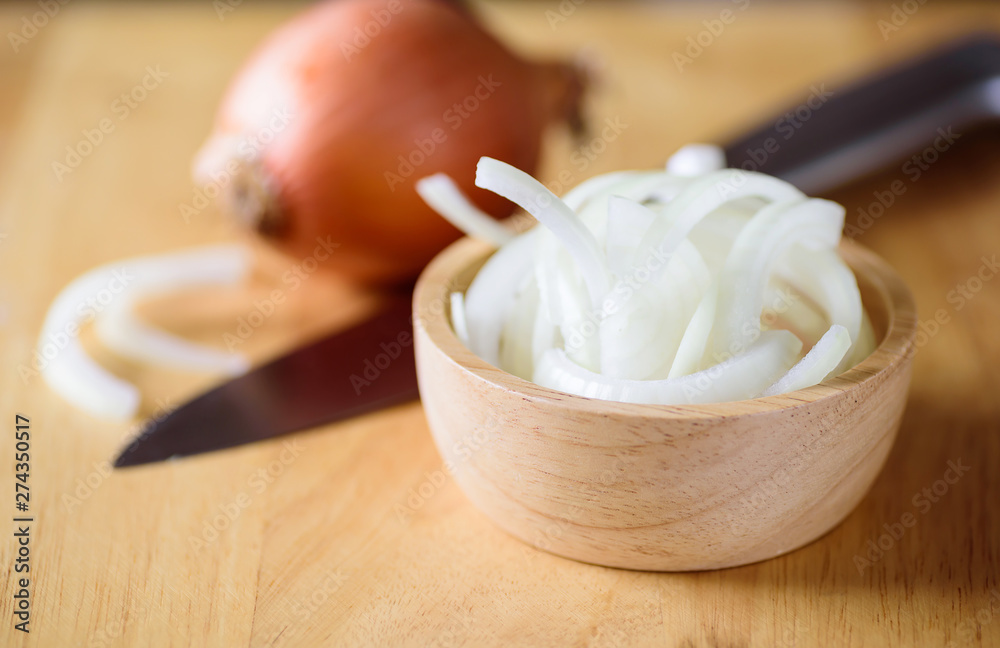 Sliced onion in a bowl on wooden board preparing for cooking Sliced onion in a bowl on wooden board preparing for cooking
