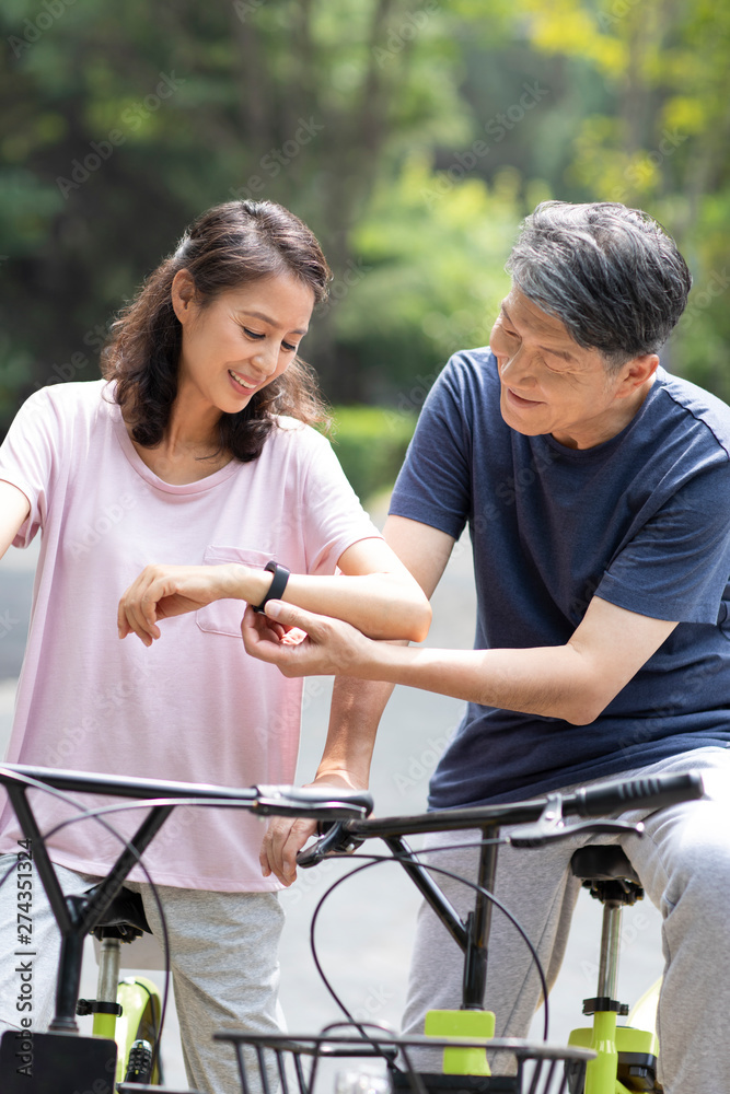 Happy mature couple checking smart watch in park Happy mature couple checking smart watch in park