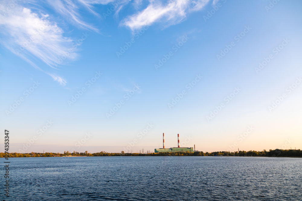 Power station on the background of a golden sunset behind the lake