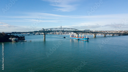 cargo ship travelling pass Auckland Harbour Bridge  with Auckland City as background