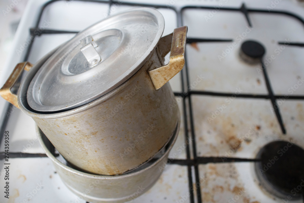Dirty pot with ladle on gas stove in dirty kitchen Dirty pot with ladle on gas stove in dirty kitchen