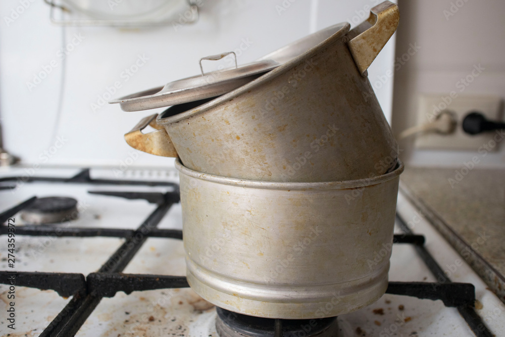 Dirty pot with ladle on gas stove in dirty kitchen Dirty pot with ladle on gas stove in dirty kitchen