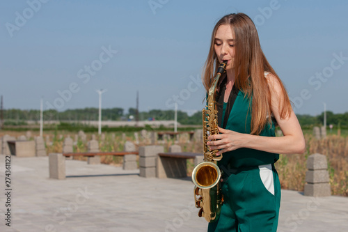 Beautiful brunette plays the saxophone in the park photo