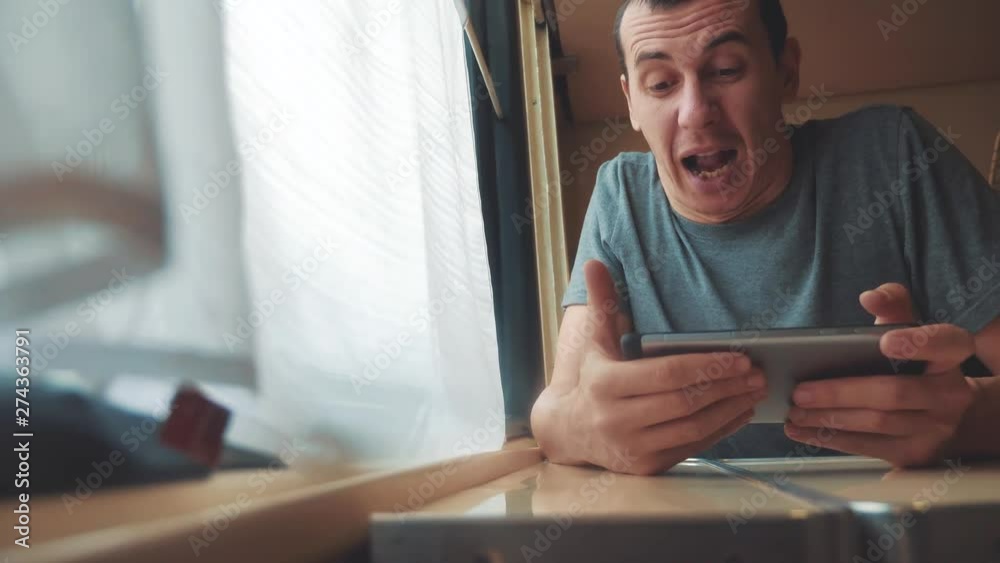 man playing an online game on a smartphone, strong emotions, anger man sitting in a train by the window. slow motion lifestyle video. train emotions joy surprise journey concept