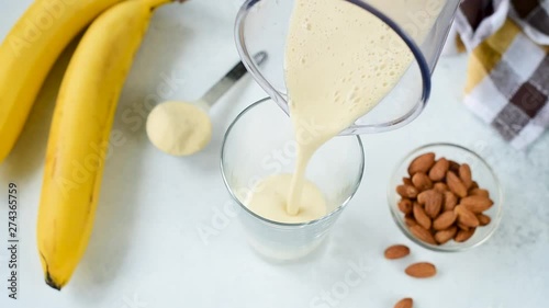 Pouring banana protein shake or smoothie in glass. Healthy eating, healthy lifestyle, weight loss and fitness concept. Vegan, vegetarian food