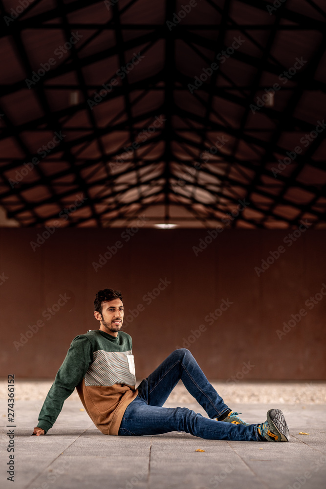 Portrait of a young man with beard and casual clothes sitting in an urban park Portrait of a young man with beard and casual clothes sitting in an urban park